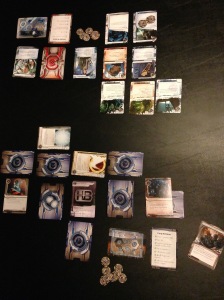 This is what a Netrunner game in progress looks like.  The Corporation (Haas-Bioroid) is below; the Runner (Gabriel Santiago, Criminal faction) is on top.